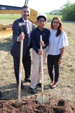 family standing with shovels, groundbreaking
